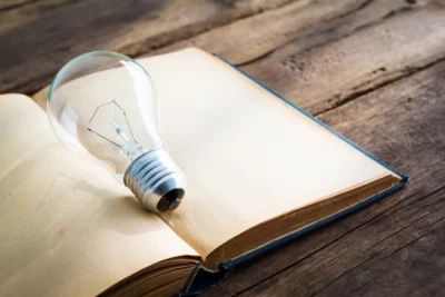 Imagem ilustrativa sobre Storytelling no Marketing, com uma lâmpada sobre um livro aberto, simbolizando ideias e criatividade na narrativa.
