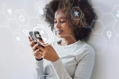 Mulher sorridente utilizando smartphone com visuais de tecnologia digital ao fundo, representando as tendências tech atuais.