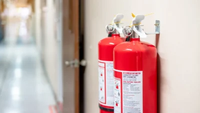 Duas extintoras de incêndio vermelhas em parede interna, essenciais para um checklist de segurança contra incêndio eficaz e prevenção de acidentes.
