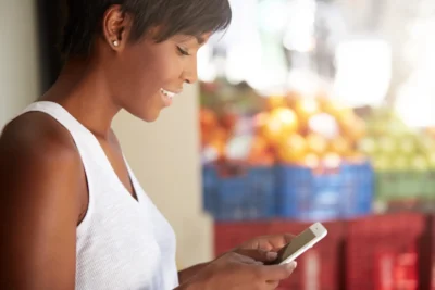 Mulher utilizando smartphone para consumir microconteúdos rapidamente, refletindo como o consumo de informações rápidas influencia estratégias de marketing digital.