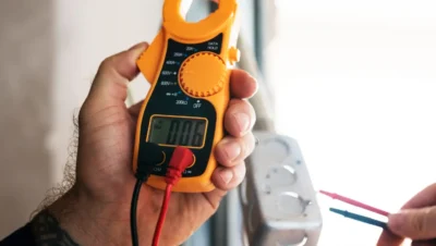 Imagem de um multímetro realizando medição elétrica, utilizado para verificar a eficiência de instrumentos de medição antes de calibrar. Importante para garantir precisão.